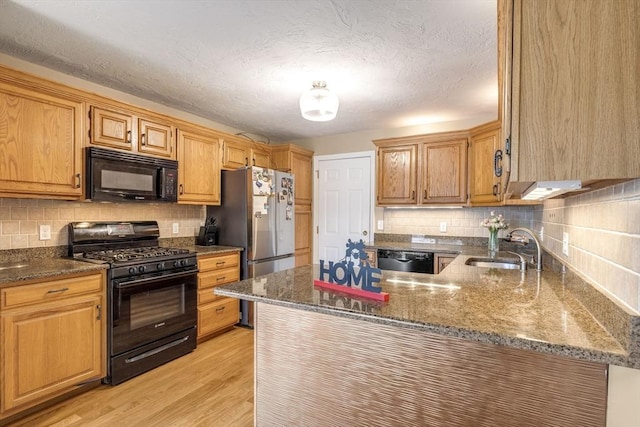 kitchen with sink, kitchen peninsula, light hardwood / wood-style floors, decorative backsplash, and black appliances