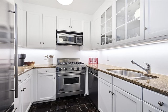 kitchen featuring dark stone countertops, white cabinetry, sink, and appliances with stainless steel finishes