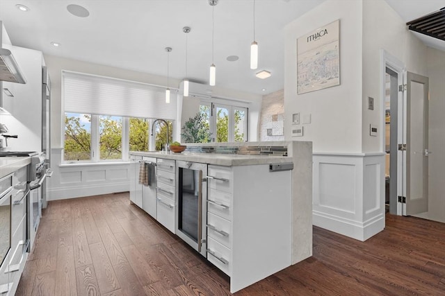 kitchen featuring wine cooler, double oven range, dark wood-style floors, a decorative wall, and white cabinets