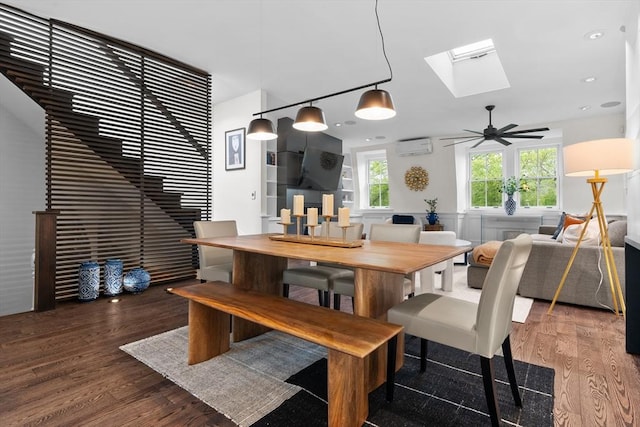 dining room with wood finished floors, a skylight, an AC wall unit, and ceiling fan
