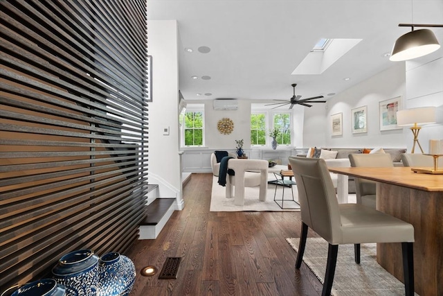 dining room with a wall mounted air conditioner, dark wood-style flooring, a skylight, a ceiling fan, and recessed lighting