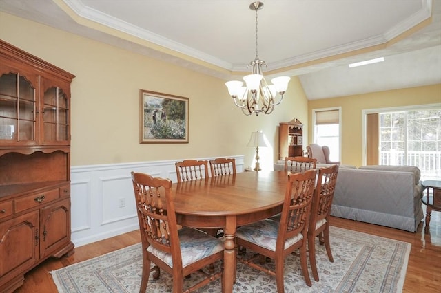 dining area featuring light wood-style flooring, a chandelier, and a tray ceiling