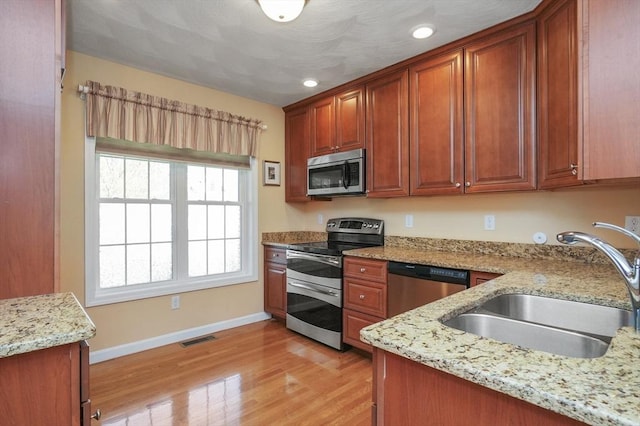 kitchen with visible vents, light wood-style floors, baseboards, a sink, and stainless steel appliances