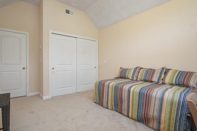 bedroom featuring visible vents, a closet, light carpet, baseboards, and vaulted ceiling