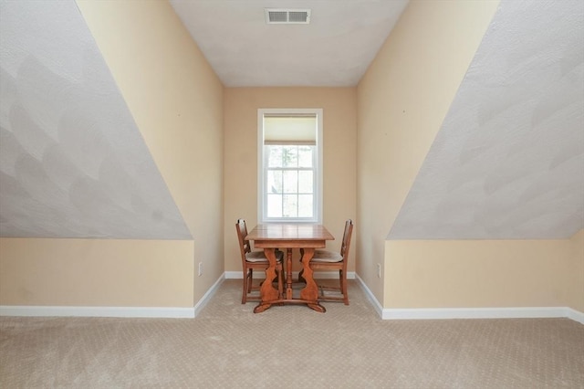 dining space with carpet flooring, baseboards, visible vents, and lofted ceiling