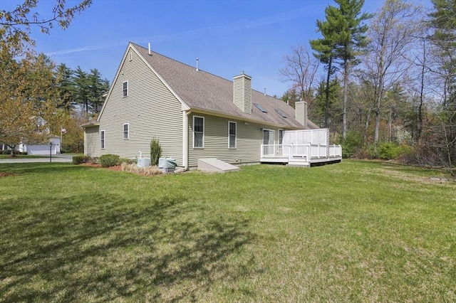 rear view of property with a lawn, a shingled roof, a wooden deck, and a chimney