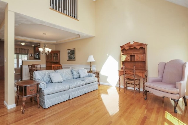 living room with light wood-type flooring, crown molding, and an inviting chandelier