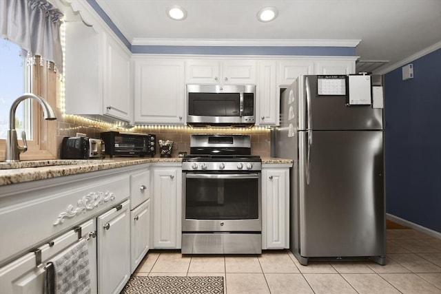 kitchen featuring a toaster, crown molding, light tile patterned floors, stainless steel appliances, and white cabinets