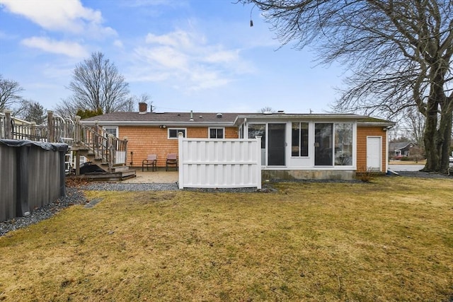 rear view of house featuring a sunroom, a lawn, and a wooden deck