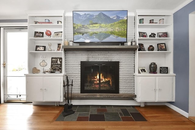 details featuring a brick fireplace, crown molding, and wood finished floors