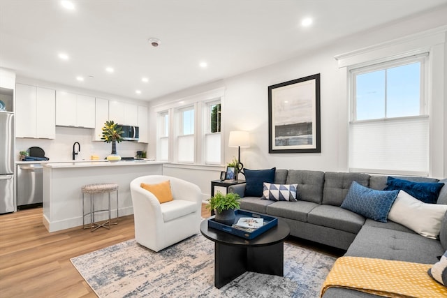 living room with sink, a healthy amount of sunlight, and light wood-type flooring