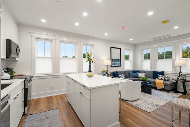 kitchen featuring light hardwood / wood-style floors, a center island, white cabinetry, and stainless steel appliances