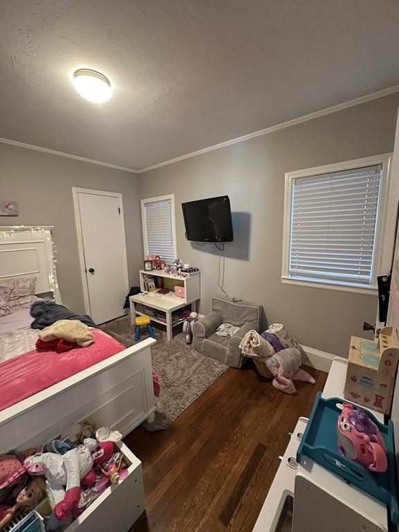 bedroom with a textured ceiling, crown molding, and dark hardwood / wood-style floors