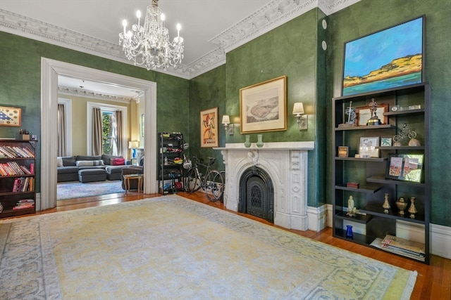 living area with crown molding, hardwood / wood-style floors, and a chandelier