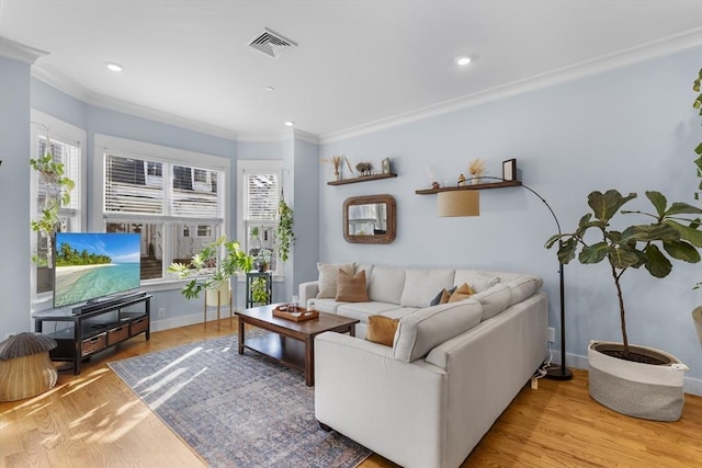 living room featuring a healthy amount of sunlight, ornamental molding, and light hardwood / wood-style flooring