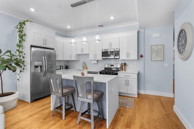 kitchen with hanging light fixtures, white cabinets, stainless steel appliances, and a kitchen island