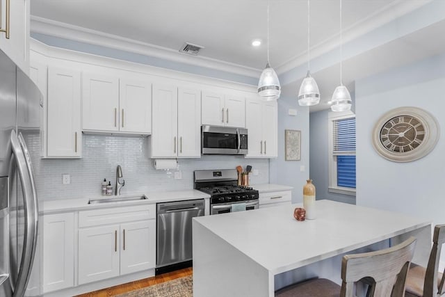 kitchen with hanging light fixtures, appliances with stainless steel finishes, sink, and white cabinetry