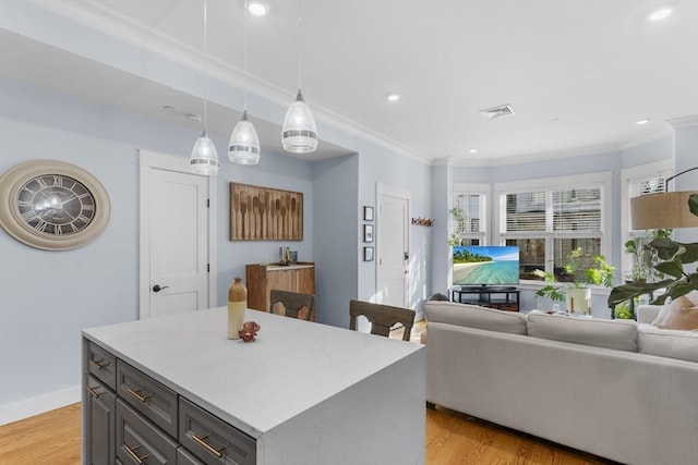 kitchen featuring decorative light fixtures, gray cabinets, a kitchen island, light hardwood / wood-style flooring, and ornamental molding