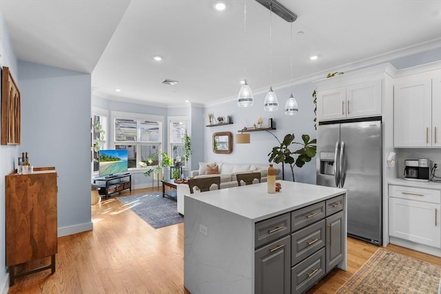 kitchen with stainless steel refrigerator with ice dispenser, gray cabinetry, decorative light fixtures, a kitchen island, and white cabinets