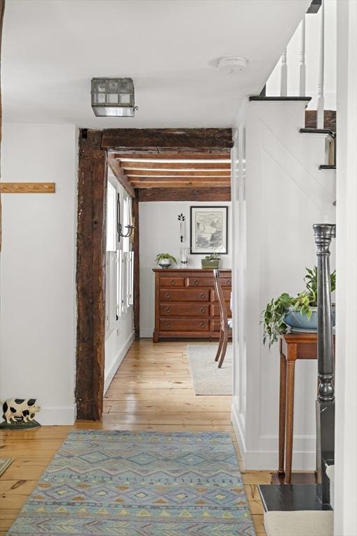 hallway featuring beamed ceiling and light hardwood / wood-style floors