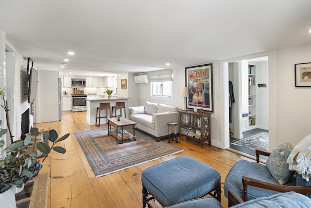 living room featuring a wall mounted air conditioner and light hardwood / wood-style floors