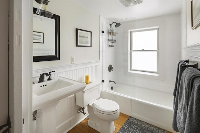 full bathroom with hardwood / wood-style flooring, a healthy amount of sunlight, toilet, and tiled shower / bath combo