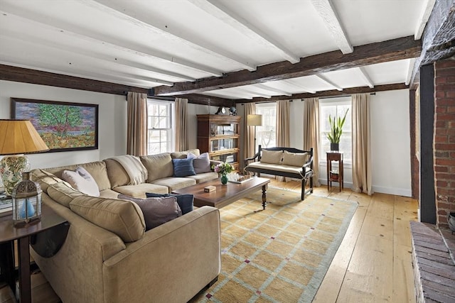 living room with a healthy amount of sunlight, beam ceiling, and light hardwood / wood-style flooring