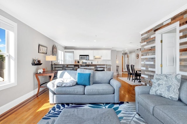 living room with crown molding, light wood-type flooring, baseboards, and recessed lighting
