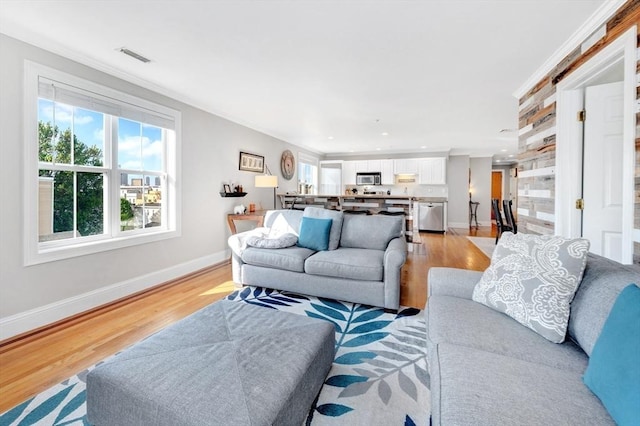 living area with crown molding, light wood-type flooring, baseboards, and recessed lighting