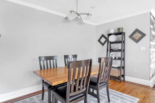 dining area featuring light wood-style floors, baseboards, ornamental molding, and a notable chandelier