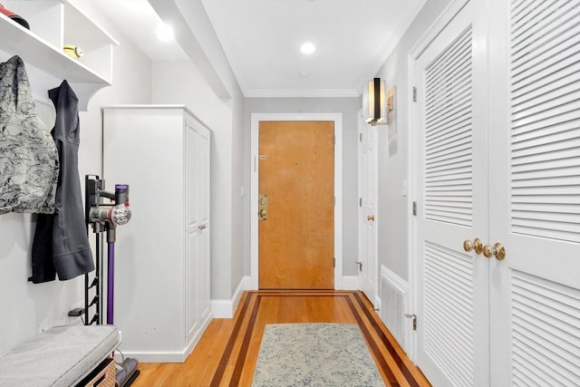 interior space featuring light wood finished floors, crown molding, and baseboards