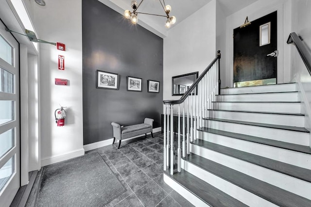 stairs featuring a towering ceiling, baseboards, and a notable chandelier