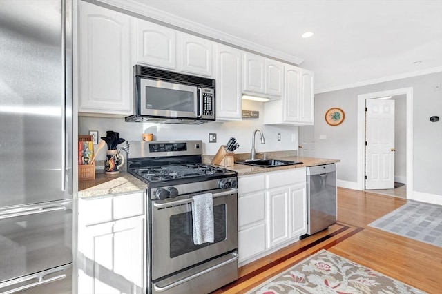kitchen featuring a sink, stainless steel appliances, light wood-type flooring, crown molding, and white cabinets