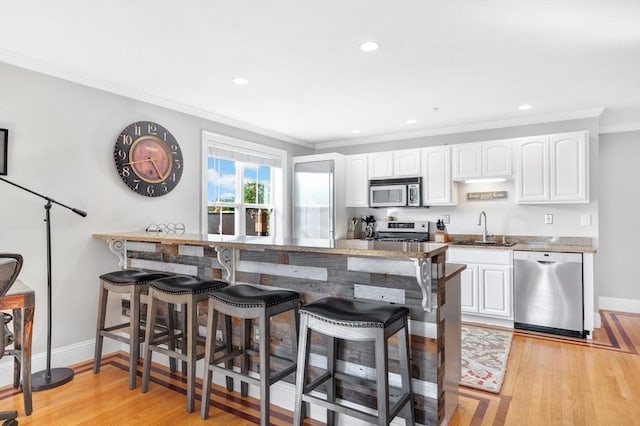 kitchen with stainless steel appliances, a breakfast bar area, a sink, and white cabinets