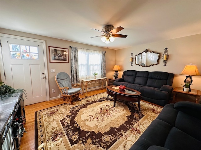 living room with ceiling fan, light wood-type flooring, and baseboard heating