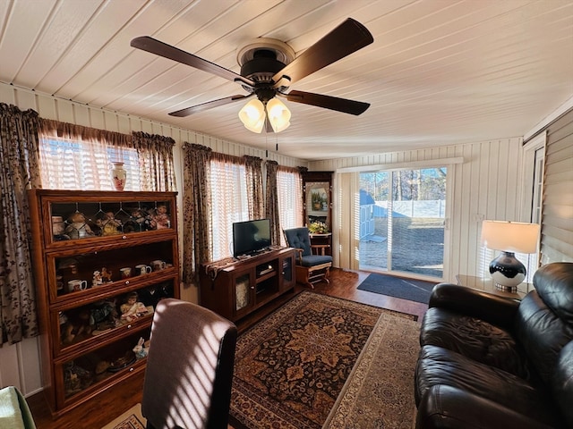 living room with hardwood / wood-style floors, wood walls, a healthy amount of sunlight, and ceiling fan