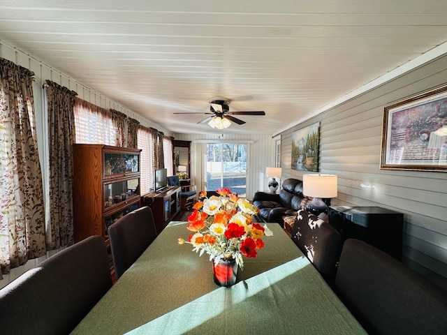 dining room featuring wood walls and ceiling fan