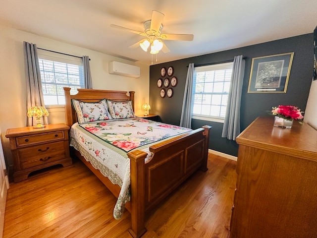 bedroom featuring a wall mounted AC, multiple windows, wood-type flooring, and ceiling fan