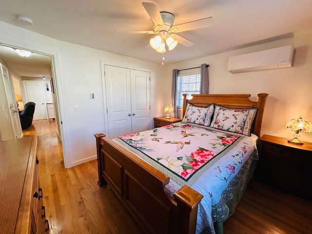 bedroom featuring an AC wall unit, a closet, hardwood / wood-style flooring, and ceiling fan