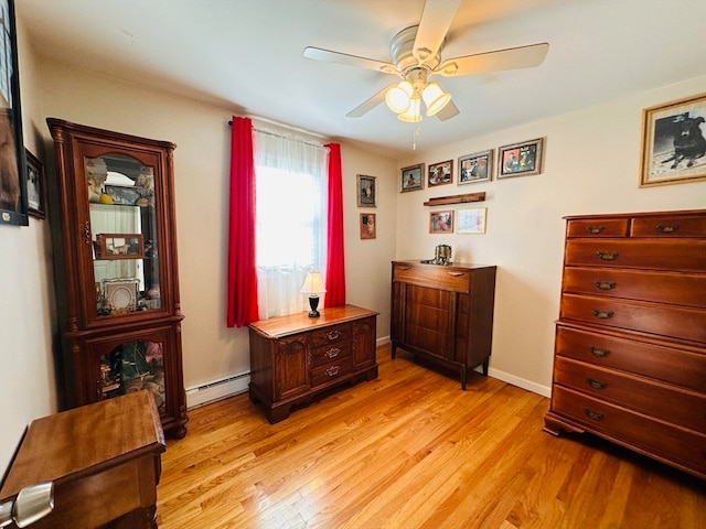 misc room with a baseboard heating unit, light wood-type flooring, and ceiling fan