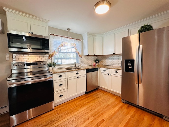 kitchen featuring light wood-type flooring, appliances with stainless steel finishes, decorative light fixtures, sink, and white cabinets