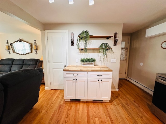 kitchen with butcher block counters, a wall mounted air conditioner, light hardwood / wood-style floors, white cabinets, and baseboard heating