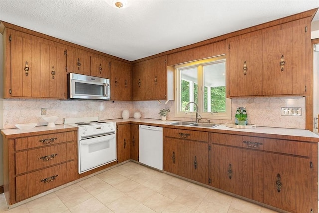 6 Lancaster Pl, Andover, MA 01810 - kitchen featuring white appliances, a sink, backsplash, brown cabinets, and light countertops