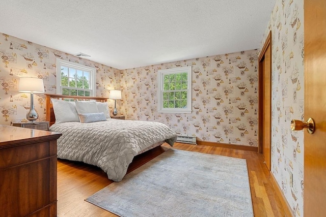 6 Lancaster Pl, Andover, MA 01810 - bedroom with baseboard heating, multiple windows, light wood finished floors, wallpapered walls, and a textured ceiling