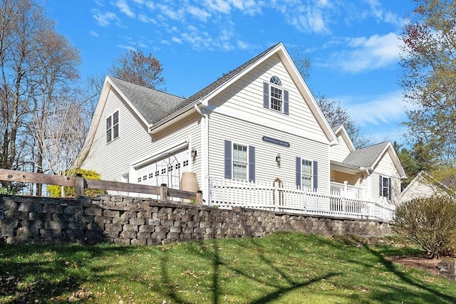 view of side of property with a yard, an attached garage, and a wooden deck