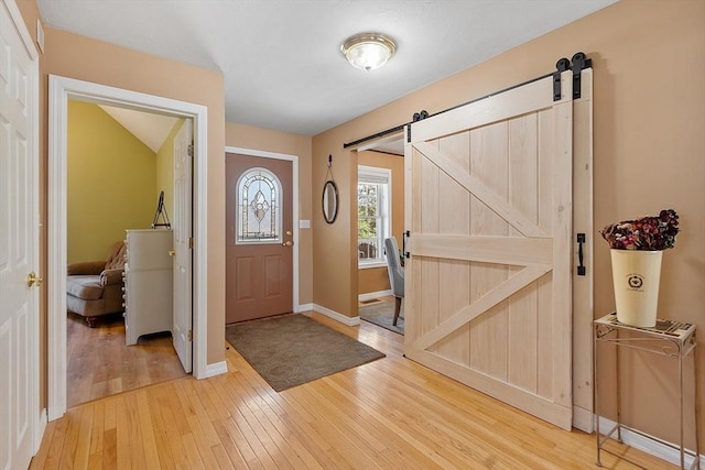 entrance foyer with a barn door, light wood finished floors, and baseboards
