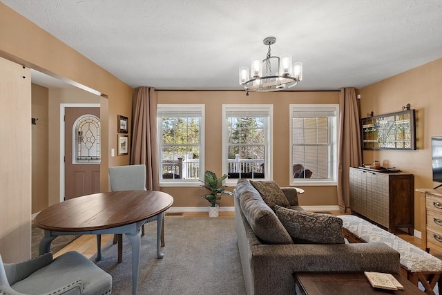 living area featuring baseboards, a notable chandelier, and carpet floors