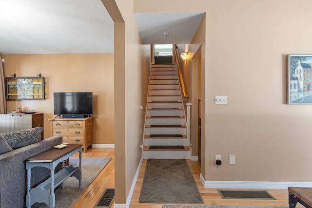 stairway with wood finished floors, visible vents, and baseboards