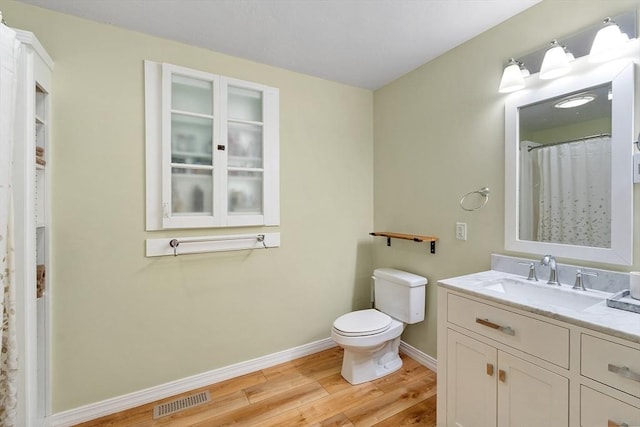 full bathroom with visible vents, baseboards, toilet, wood finished floors, and vanity