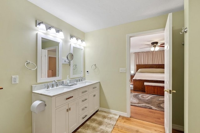 ensuite bathroom featuring double vanity, a sink, wood finished floors, and ensuite bathroom